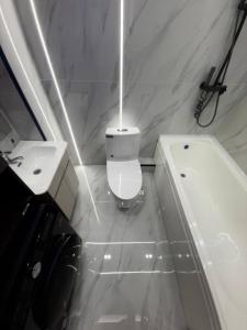 a white bathroom with a toilet and a sink at Modern Luxury Apartment Central Samarkand in Samarkand +4 photos