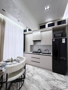 a kitchen with a black refrigerator and a table at Modern Luxury Apartment Central Samarkand in Samarkand