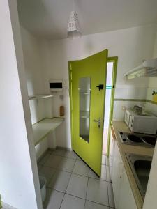 a kitchen with a green door in a kitchen at Studio N10 Résidence OBAYEAR in Schœlcher
