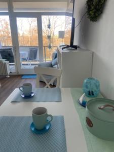 a living room with two coffee cups on the floor at Modernes Apartment mit Pool und Sauna in Möhnesee
