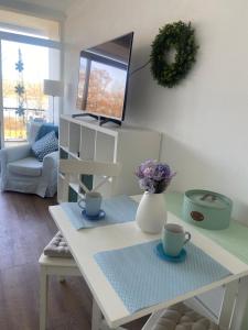 a living room with a white table and a tv at Modernes Apartment mit Pool und Sauna in Möhnesee