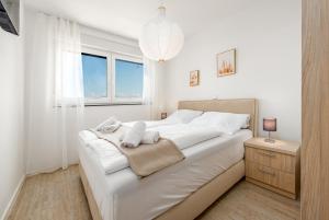 a white bedroom with a large bed and a window at Villa Mare e Monti in Nin