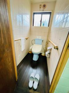 a bathroom with a toilet and a pair of slippers at 与那国島一棟貸切宿はいぬきち in Yonaguni