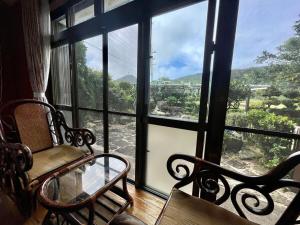 a room with a window with a chair and a glass table at 与那国島一棟貸切宿はいぬきち in Yonaguni +5 photos