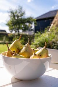 a white bowl of pears sitting on a table at Unieke plaggenhut in Drenthe met bedstee & uitzicht op wijngaard in Ruinerwold +18 photos