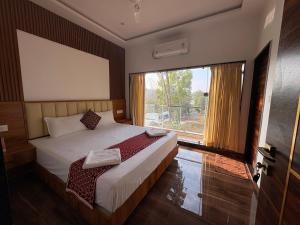 a bedroom with a bed and a large window at Riverside Resort Yelagiri in Yelagiri