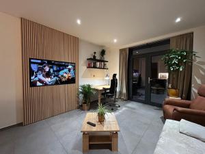 a living room with a tv on a wall at Appartement de Standing Plein Centre-Ville "L Atelier de Joss" in Bastogne