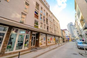 a street with buildings and a car parked on a street at Stan na dan DM Uzice in Užice