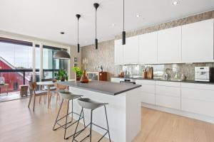 a kitchen with white cabinets and a island with bar stools at Svolvær Panorama City Suite in Svolvær +15 photos
