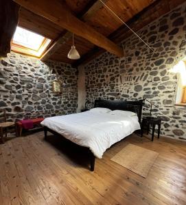 a bedroom with a large bed in a stone wall at Le Petit Moras in Chomérac +47 photos