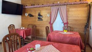 ein Esszimmer mit zwei Tischen und einem Fernseher in der Unterkunft Hotel Al Pelmo in Pieve di Cadore