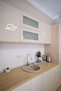 a kitchen with a sink and white cabinets at ASTI Residence Aparthotel in Năvodari +66 photos