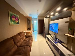 a living room with a couch and a television at Apartment Borneo Bay City - AH Property Indonesia in Balikpapan