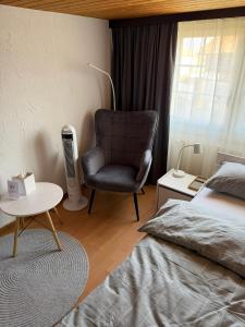 a bedroom with a chair and a bed and a table at Gästehaus Eichberg, Rheintal in Eichberg