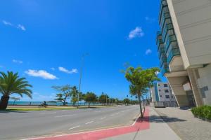 an empty street in front of a building with palm trees at Flat PRAIA de Camburi in Vitória