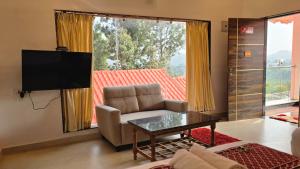 a living room with a couch and a table and a television at Riverside Resort Yelagiri in Yelagiri
