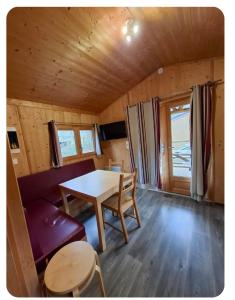 a dining room with a table and a couch in a cabin at Cabane bois insolite vue montagne piscines famille in Laruns