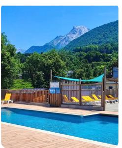 a swimming pool with chairs and a mountain in the background at Cabane bois insolite vue montagne piscines famille in Laruns