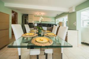 a dining room with a glass table and white chairs at Cocon des dunes in Camiers