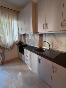 a kitchen with white cabinets and a sink at Velvet studios Ioanna in Naousa