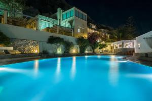 a swimming pool in front of a building at night at Antinea Suites Hotel & Spa in Kamari