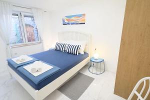 a bedroom with a bed with blue sheets and a window at Apartman Lucija in Selce