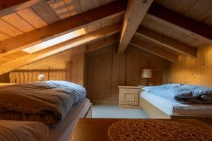 two beds in a room with wooden walls at Post Hotel Moena in Moena