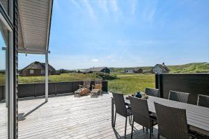 a wooden deck with chairs and a table on it at 392-Harboore-Fourmivej-64 in Harboør