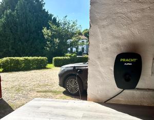 a car plugged into a wall with a parking meter at Gut Petersdorf Lensahn - ideal für Familien und Hunde - mit Kamin, Parkblick, Terrasse, eingezäuntem Garten und E-Ladestation in Lensahn