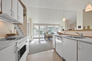 a kitchen with white cabinets and a dining room at 0379-Romo-Stormengevej-14 in Høm +15 photos