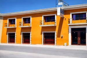 an orange building with balconies on a street at Hotel PREMIER in Linares