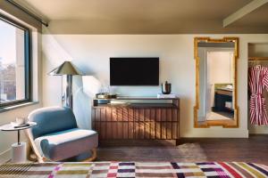 a living room with a tv and a chair and a mirror at All Inn Hotel in Denver