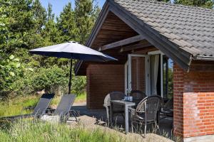 a patio with a table and an umbrella at 0326-Romo-Sandloberen-3 in Høm