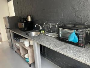 a kitchen counter with a microwave and a sink at Blue Moon Charming 2 Bed Poolside Apartment in Bellville