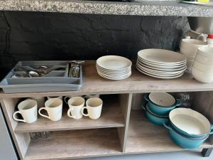 a kitchen shelf with plates and cups and a sink at Blue Moon Charming 2 Bed Poolside Apartment in Bellville