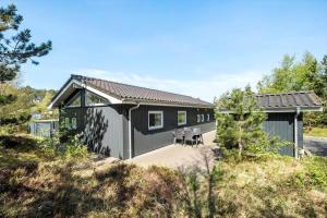 a small black house with a patio in a field at 0403-Romo-Lyngvejen-44-C in Høm