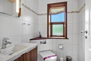 a bathroom with a toilet and a sink and a window at 0335-Romo-Vestergardsvaenget-2 in Høm +14 photos