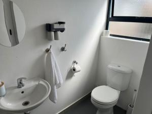 a white bathroom with a toilet and a sink at Blue Moon Charming 2 Bed Poolside Apartment in Bellville +9 photos
