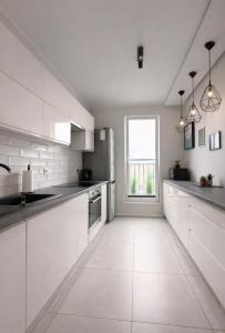 a kitchen with white cabinets and a large window at Modern 2-Room Apartment with Large Balcony & Private Parking in Gdańsk
