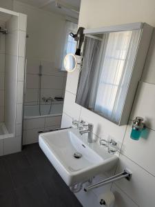 a white bathroom with a sink and a mirror at Gästehaus Eichberg, Rheintal in Eichberg +78 photos