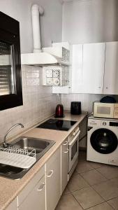 a kitchen with white cabinets and a sink and a stove at Sweet Studio in Leptokarya