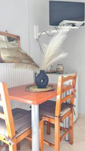 a wooden table with two chairs and a vase on it at Sweet Studio in Leptokarya