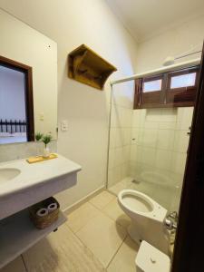 a bathroom with a toilet and a glass shower at Jeromia Casa e Pousada in Rifaina