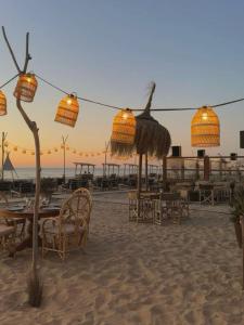a beach with tables and chairs and a sunset at Santos in Noordwijk aan Zee