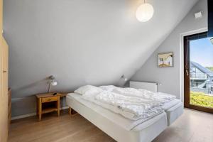 a white bedroom with a bed and a table at 0344-Romo-Vestergade-331 in Høm