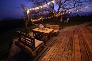 a wooden table and benches with lights on a deck at Osada na hůrce in Hustopeče