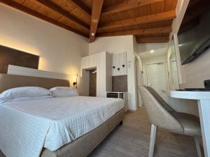 a bedroom with a white bed and a desk at Hotel Roma in Garda