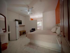 a white bedroom with a bed and a refrigerator at Royal Pacífico Manzanillo in Manzanillo