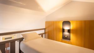a room with two beds and a light on the wall at Kyriad ECO - Lorient Lanester in Lanester +57 photos