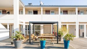 a building with a picnic table and potted plants at Kyriad ECO - Lorient Lanester in Lanester